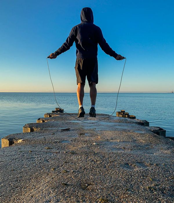 Silhouette of a man stretching at sunrise, symbolizing renewed energy.